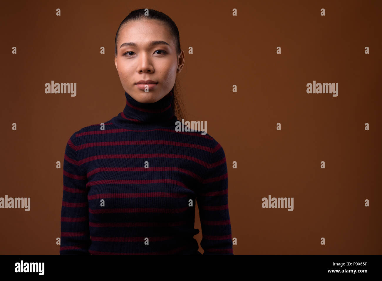Young beautiful Asian transgender woman against brown background Stock Photo