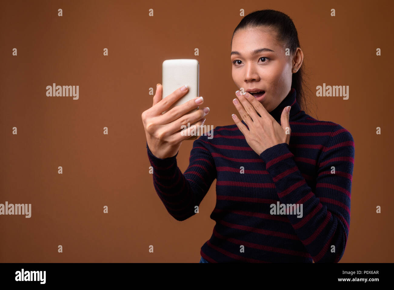 Young beautiful Asian transgender woman against brown background Stock Photo