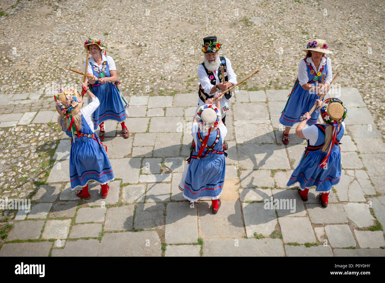 Morris dancers dressed in traditional costumes bang sticks and ...