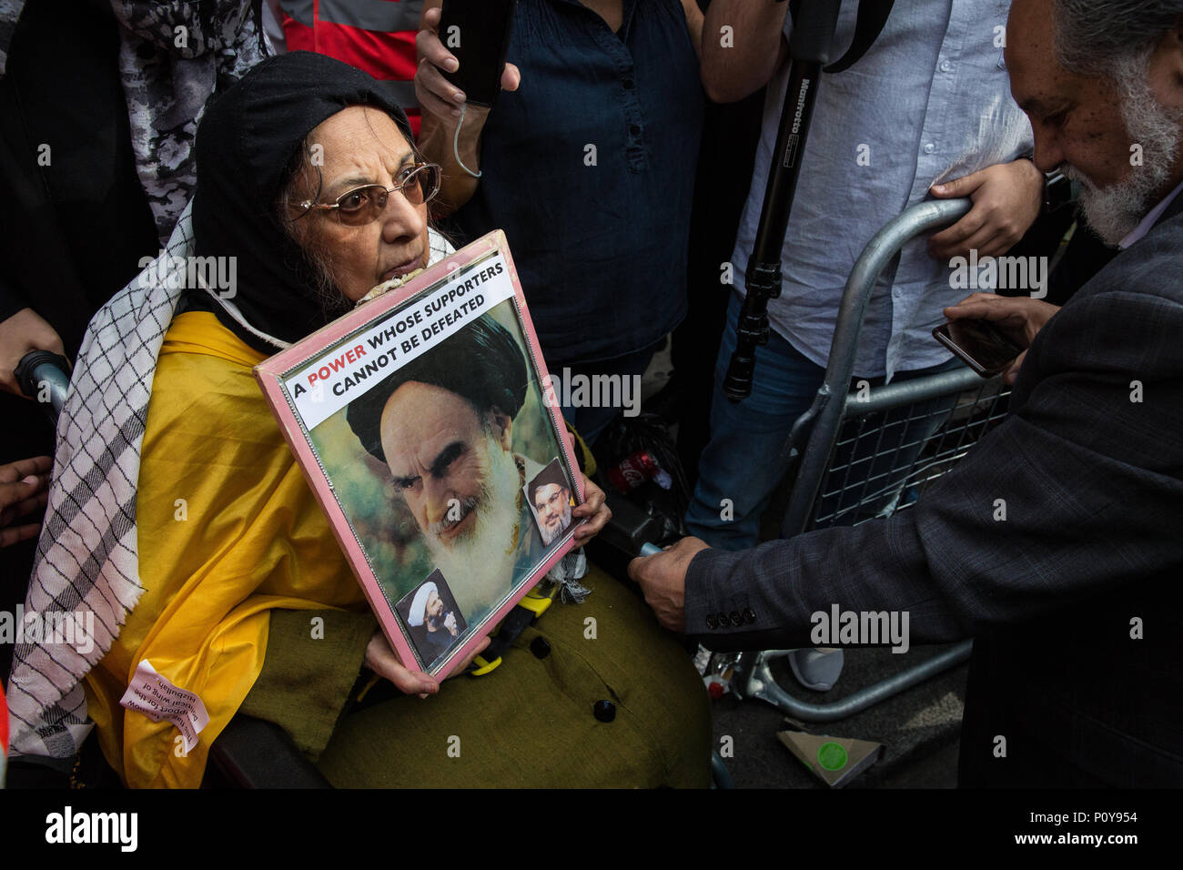 London, UK. 10th June, 2018. A woman in a wheelchair holding an image of the Supreme Leader of Iran Sayyid Ali Hosseini Khamenei is assisted in joining the pro-Palestinian Al Quds Day march organised by the Islamic Human Rights Commission after pro-Israel counter-protesters had tried to block her. An international event, it began in Iran in 1979. Quds is the Arabic name for Jerusalem. Credit: Mark Kerrison/Alamy Live News Stock Photo