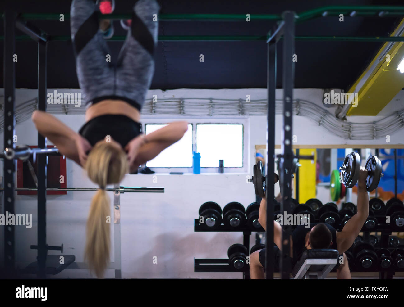 athlete woman doing abs exercises hanging upside down on horizontal bar