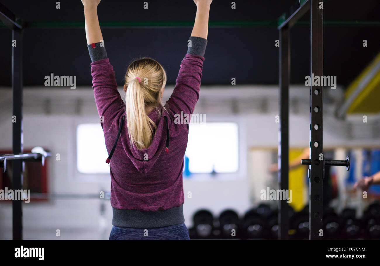 young muscular woman doing pull ups on the horizontal bar as part of ...