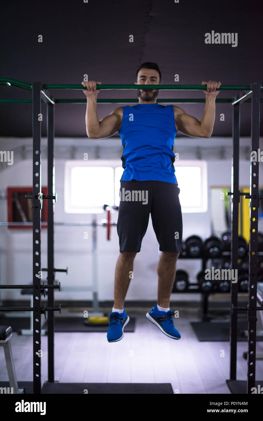 young muscular man doing pull ups on the horizontal bar as part of ...