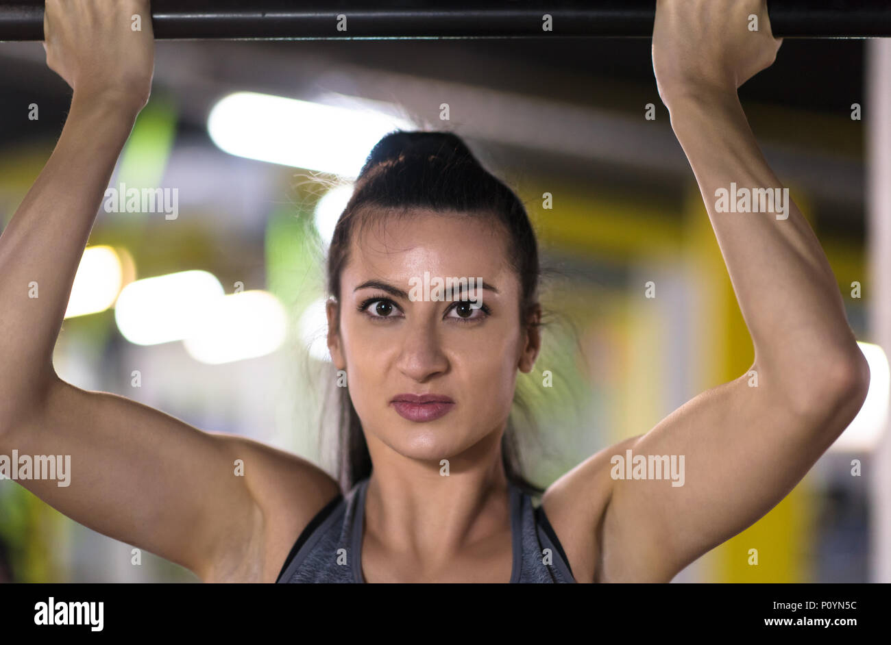 young muscular woman doing pull ups on the horizontal bar as part of ...