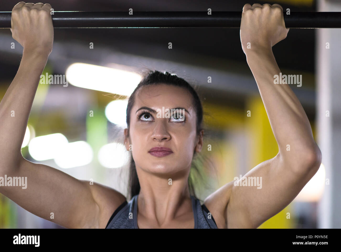 young muscular woman doing pull ups on the horizontal bar as part of ...