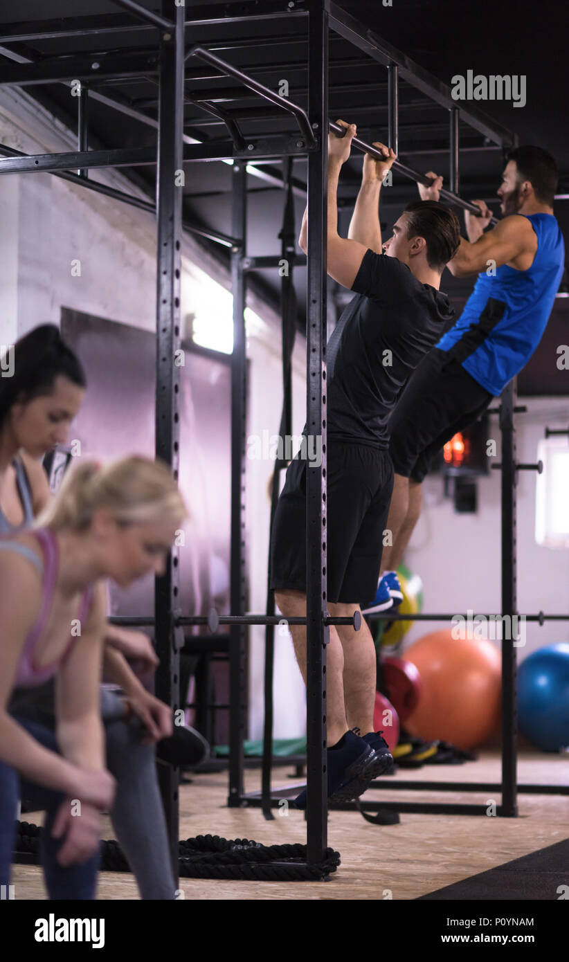group of young muscular athletes doing pull ups on the horizontal bar ...