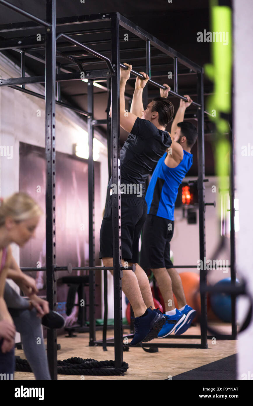 group of young muscular athletes doing pull ups on the horizontal bar ...