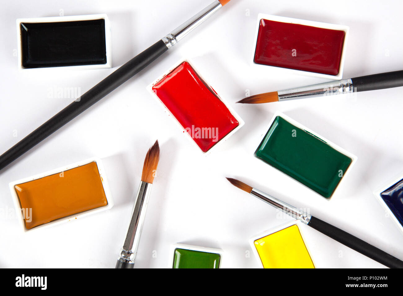 Solid watercolor pans set and paint brushes top view on white