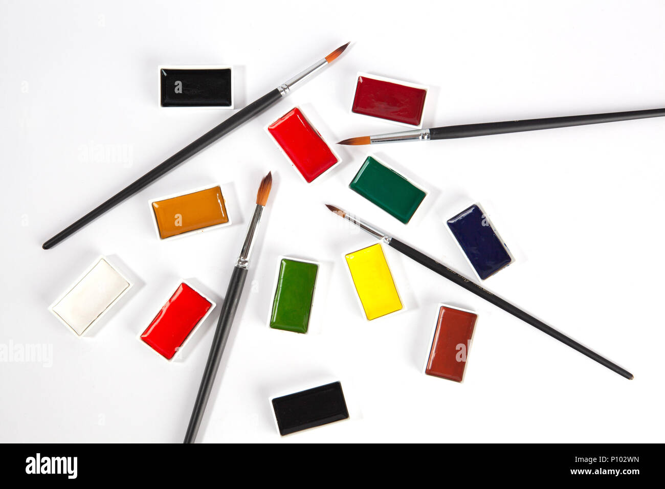 Watercolor pans colorful set and paint brushes top view on white