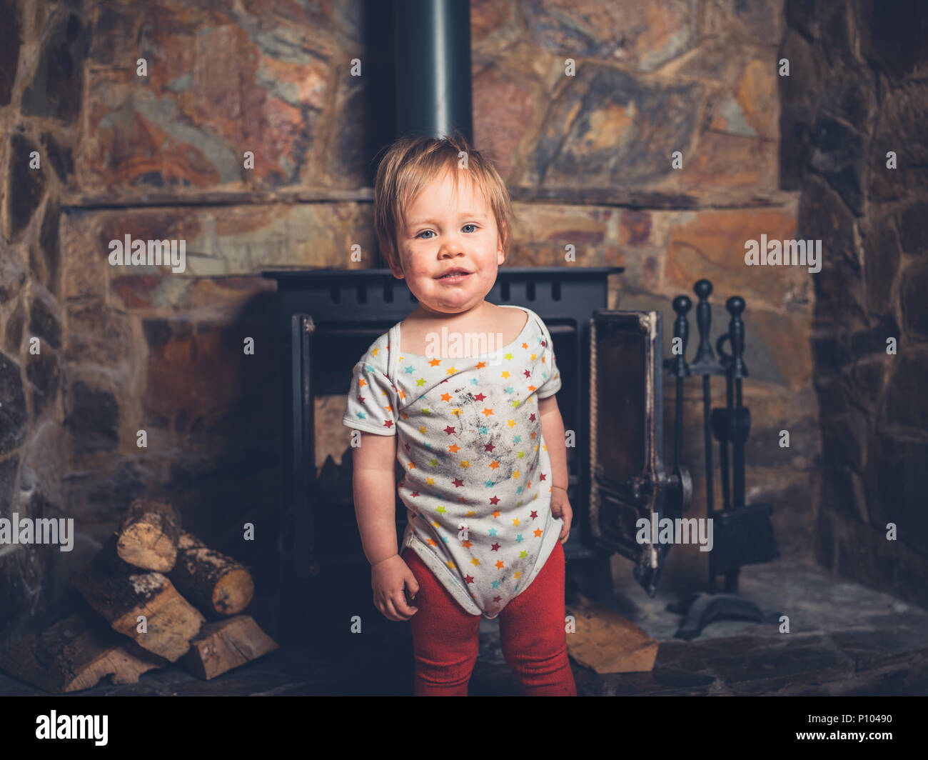A happy little boy is covered in sud and dirt from playing with a log burner Stock Photo