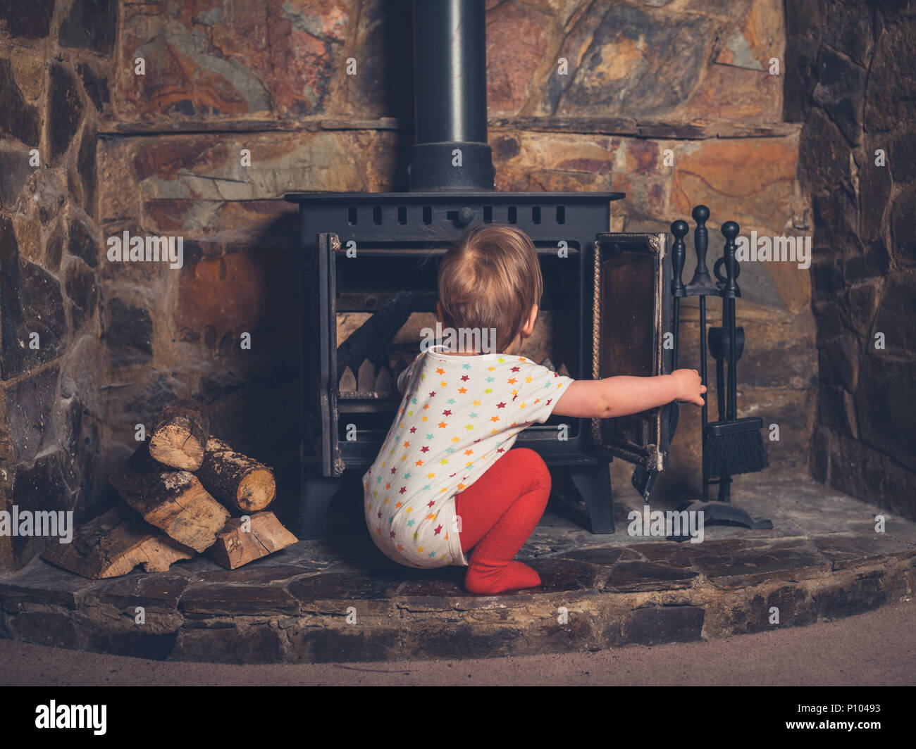 A little boy is playing with the log burner Stock Photo
