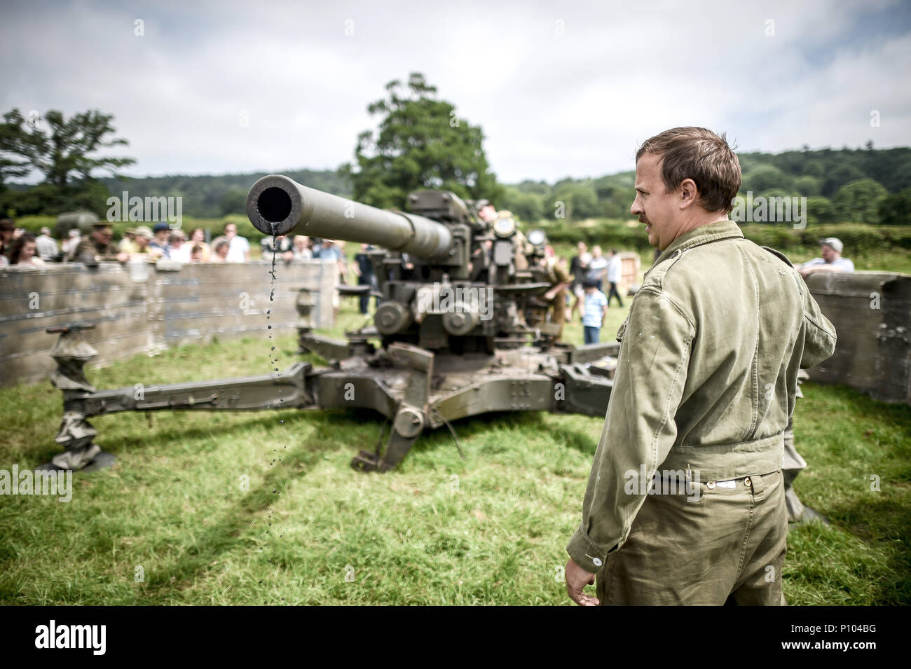 A man dressed as a WWII soldier checks for water at the end of an anti-aircraft gun after a firing demonstration at the Dig for Victory Show, a festival that celebrates the 1940's, at the North Somerset Ground, Wraxall, Somerset. Stock Photo