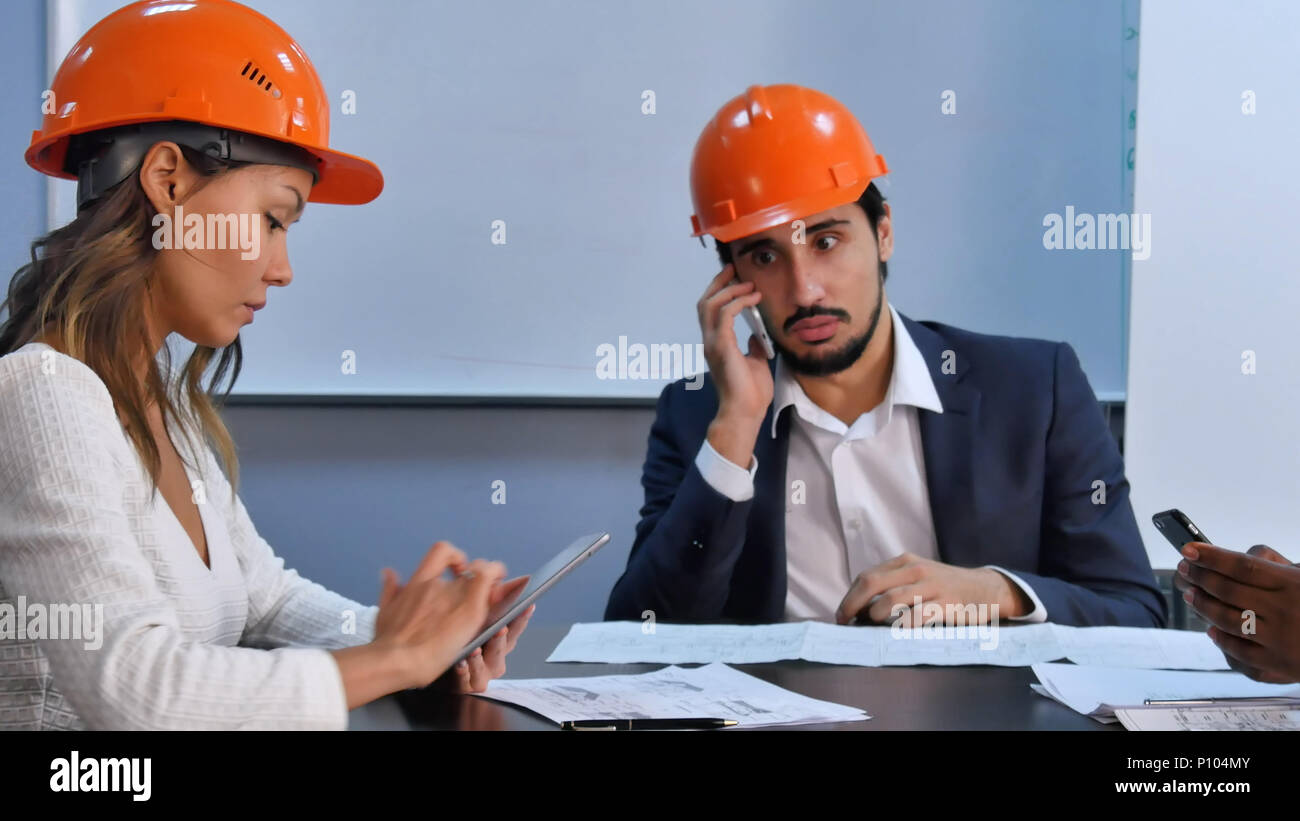 Executive team using smartphone and digital tablet sitting in office Stock Photo
