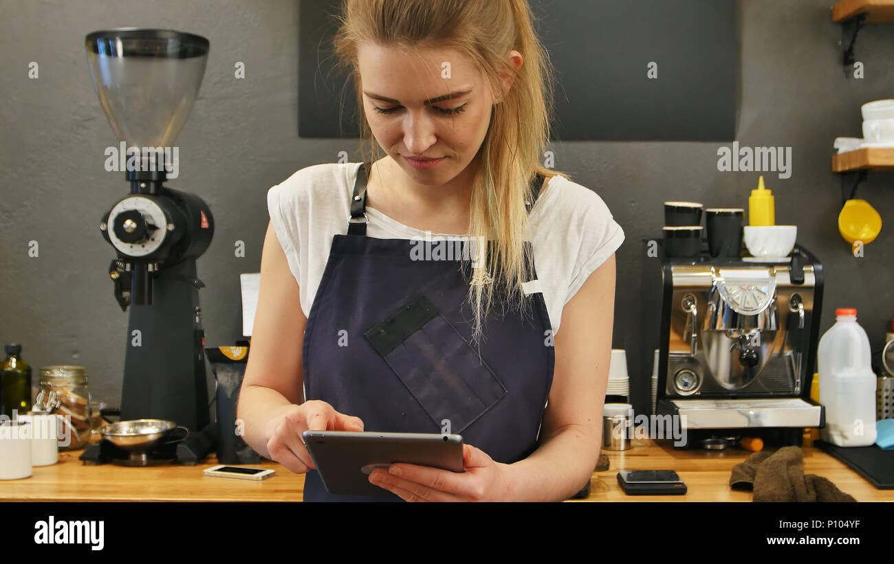 Smiling and cheerful barista using digital tablet for work Stock Photo