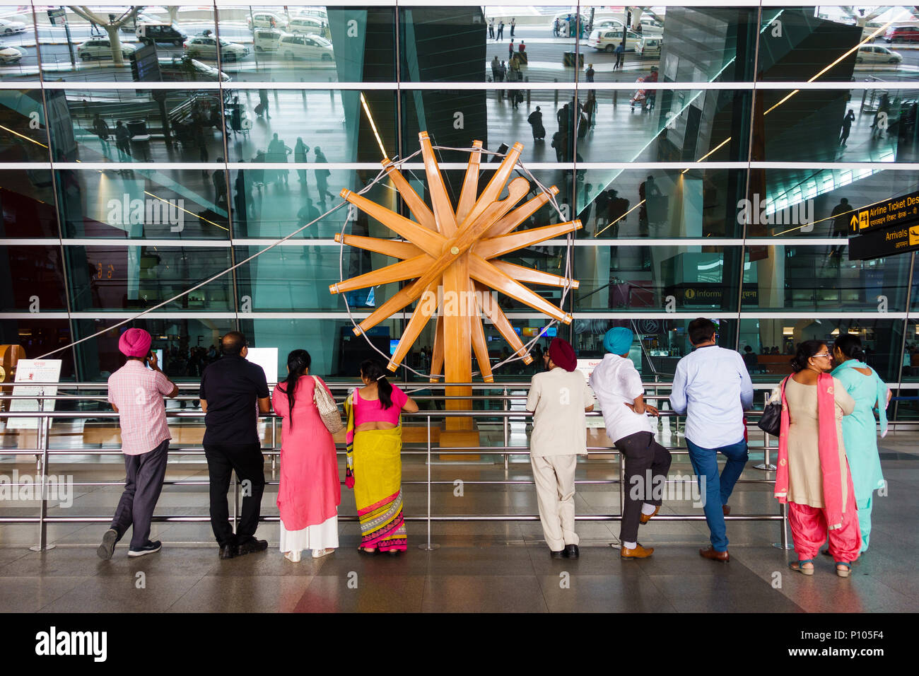 NEW DELHI, INDIA - CIRCA APRIL 2017: People stand in front of the world's largest charkha (spinning wheel) at Indira Gandhi International Airport. Stock Photo