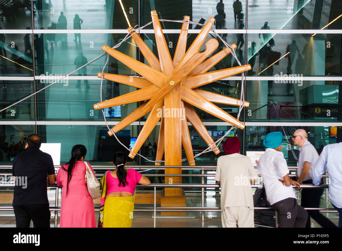 NEW DELHI, INDIA - CIRCA APRIL 2017: People stand in front of the world's largest charkha (spinning wheel) at Indira Gandhi International Airport. Stock Photo