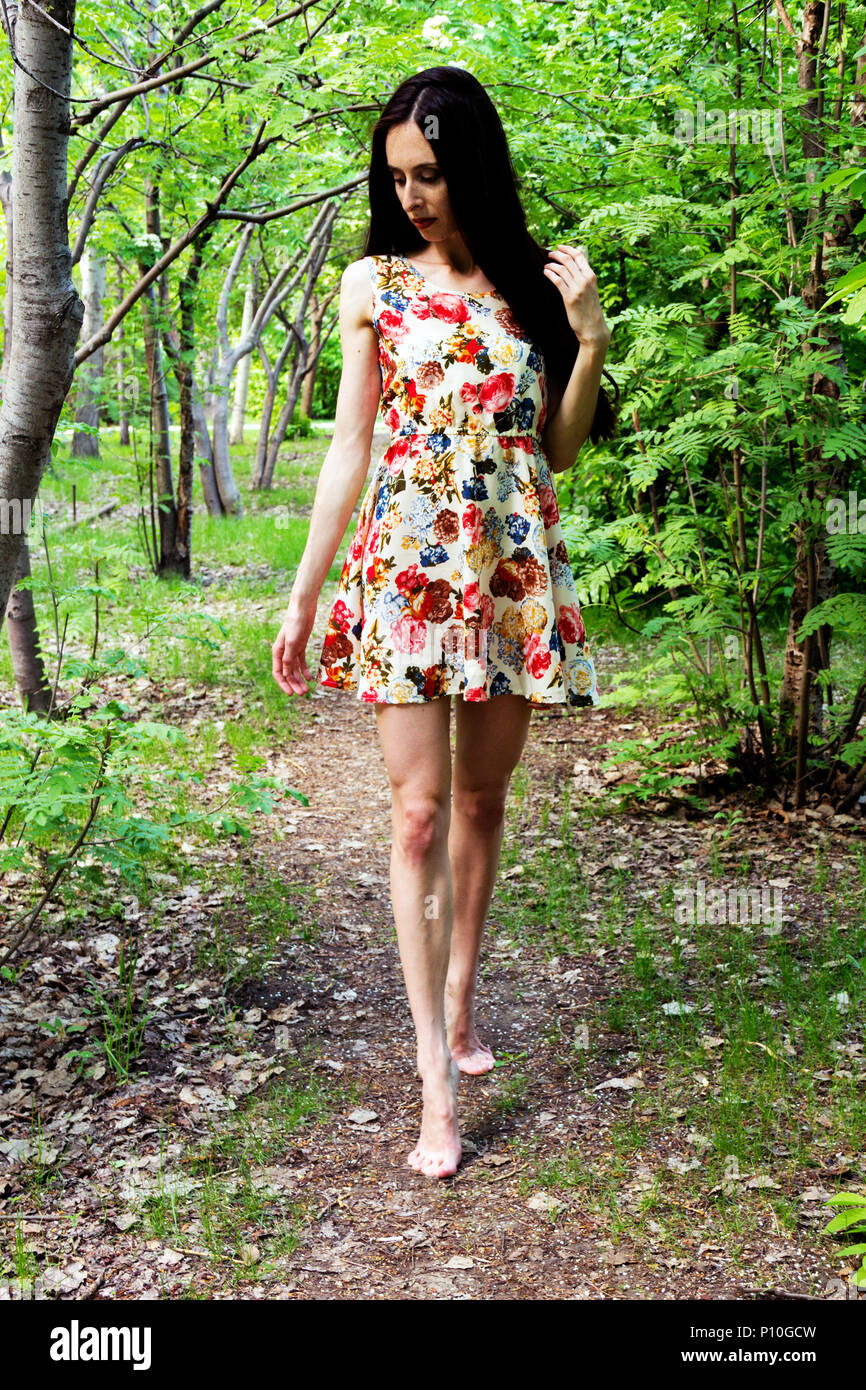 A barefoot woman in a dress with long black hair walks in the forest Stock  Photo - Alamy