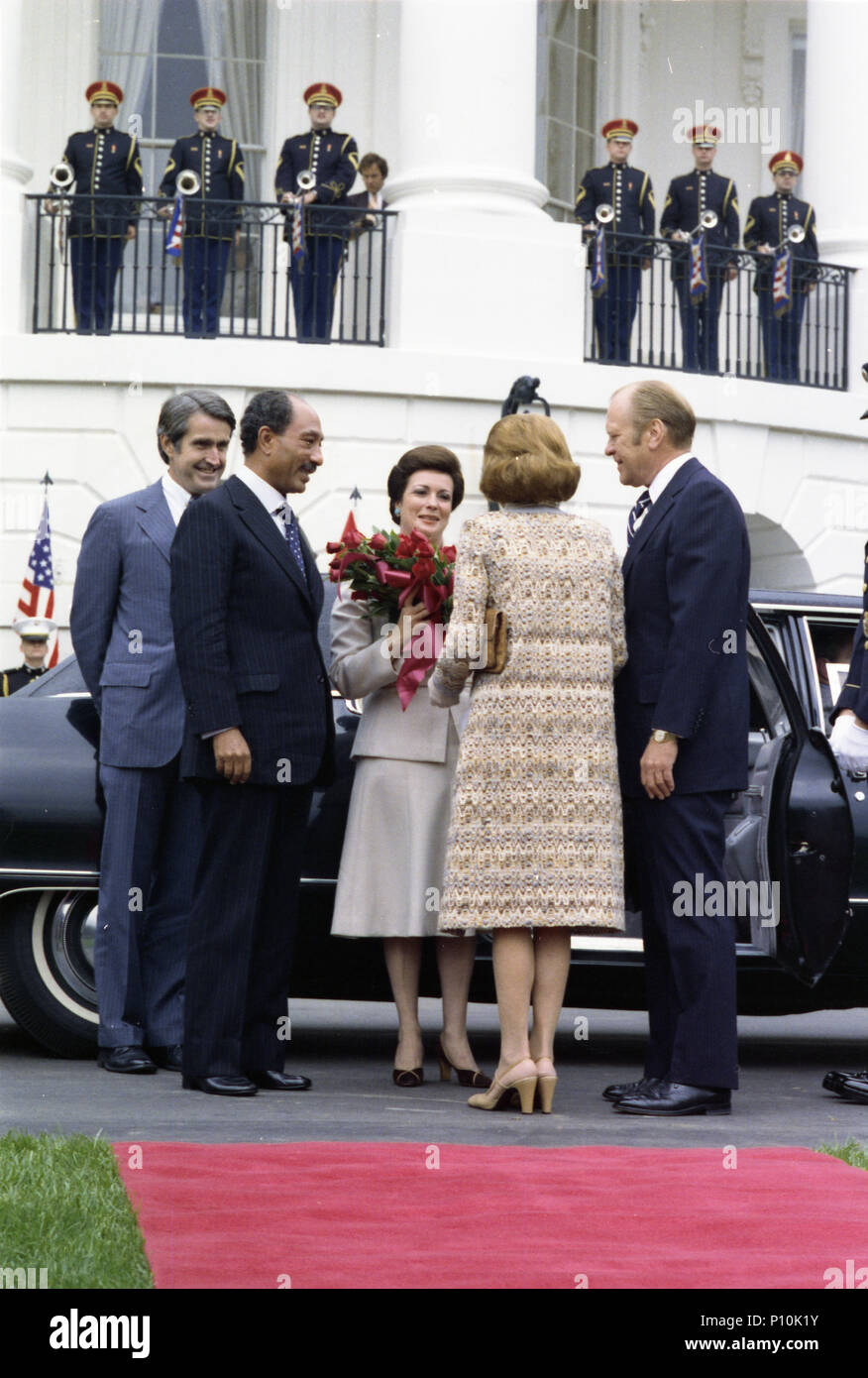 1975, October 27 – South Driveway – The White House –  Gerald R. Ford, Betty Ford; President & Mrs. Al-Sadat; Marine Corps Band; Henry Catto – Fords greet Sadats at limousine, roses given to Mrs. Al-Sadat; Betty Ford’s back to camera – State Visit of Egyptian President & Mrs. Anwar Al-Sadat - Arrival Ceremony Stock Photo