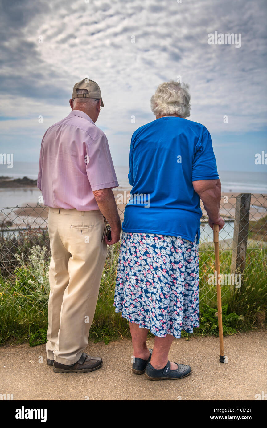 An elderly couple watch the sun go down together. Stock Photo