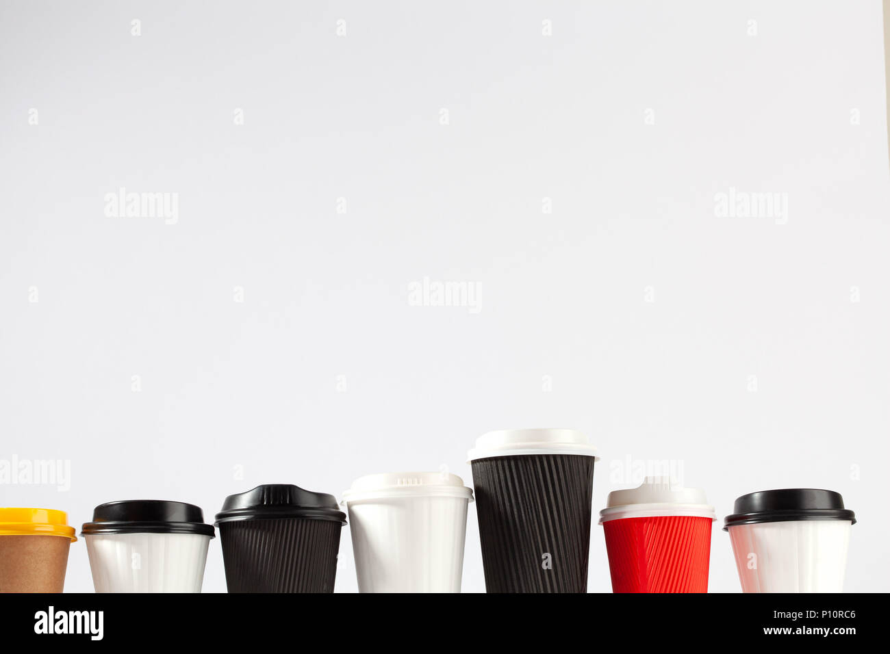 Row of plastic blank coffee cups with lids of various sizes and colors