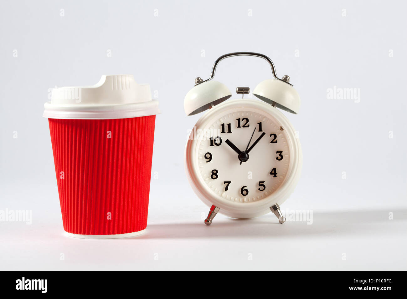 Red plastic coffee cup and vintage alarm clock isolated on white Stock