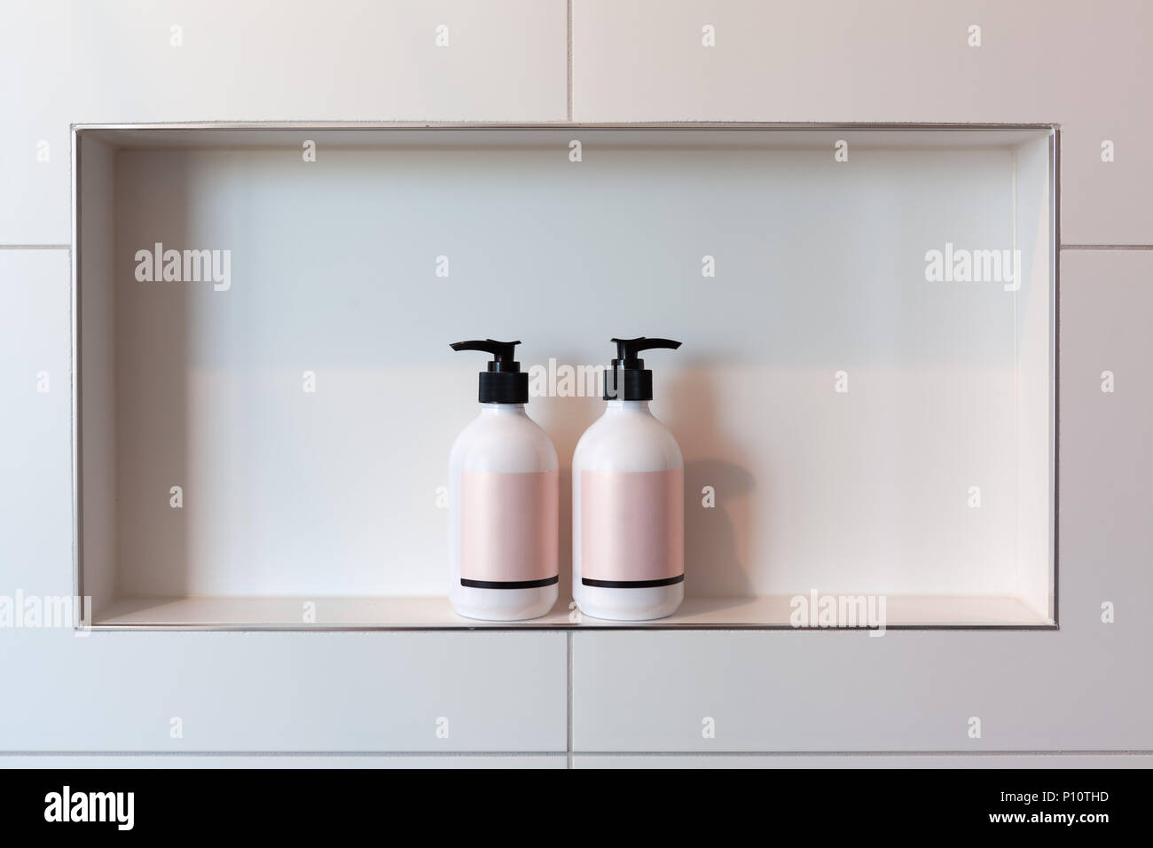 Disagreement concept - two liquid dispensers facing away from each other in shower niche with copy space Stock Photo