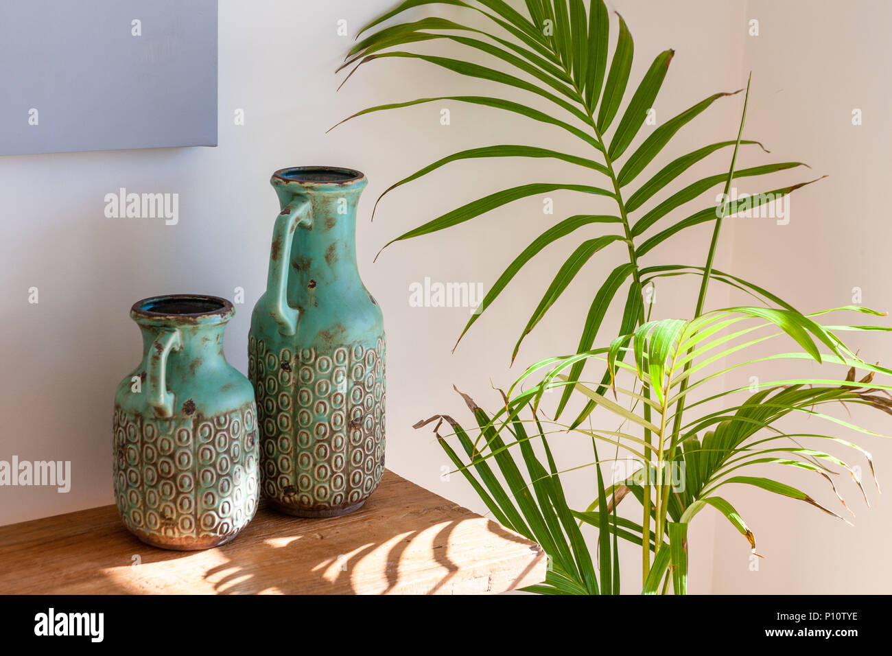 Two decorative vases on wooden table and Majesty Palm in sunlight - cozy home scene Stock Photo
