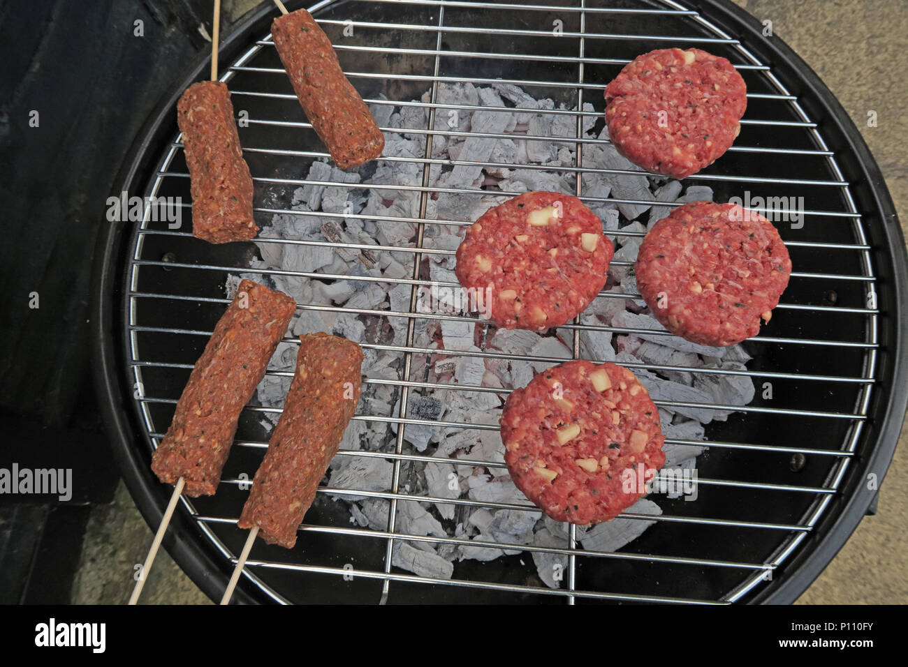 Dangers of food poisoning from summer BBQ meat, Sausages, beef burgers, Kebabs, under-cooked or raw Stock Photo