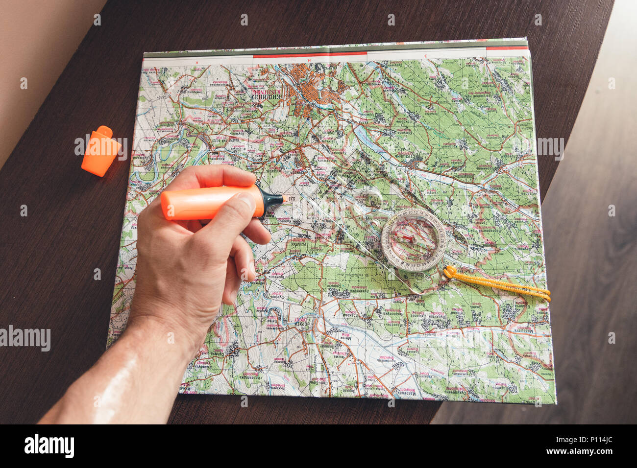 Man holding an orange marker above a map looking for a path Stock Photo