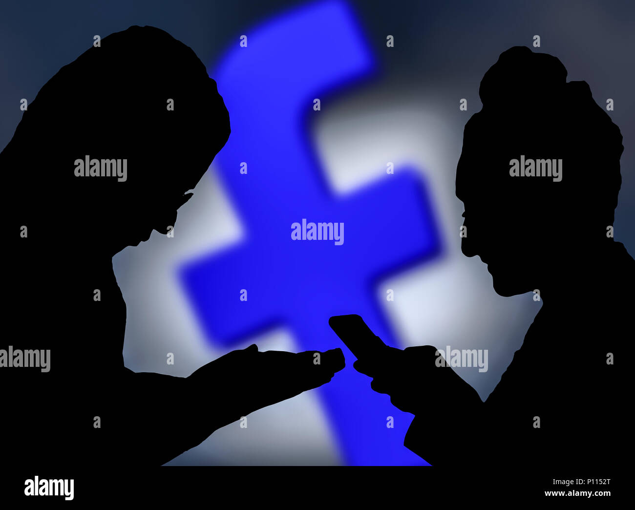 Silhouettes of a couple of people using the Facebook app on smartphones. Stock Photo
