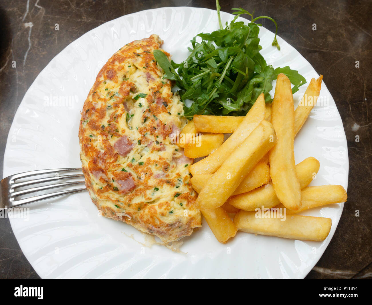 Lunch a Ham and Cheddar Cheese omelette served with fresh rocket salad and potato chips on white