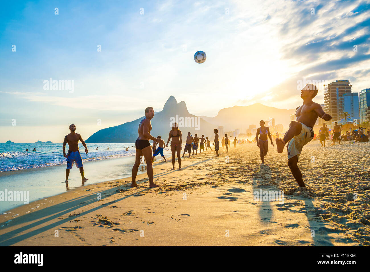 RIO DE JANEIRO - APRIL 01, 2014: Groups of young Brazilians play keepy uppy, or altinho, at sunset on the shore of Ipanema Beach at Posto 9 Stock Photo