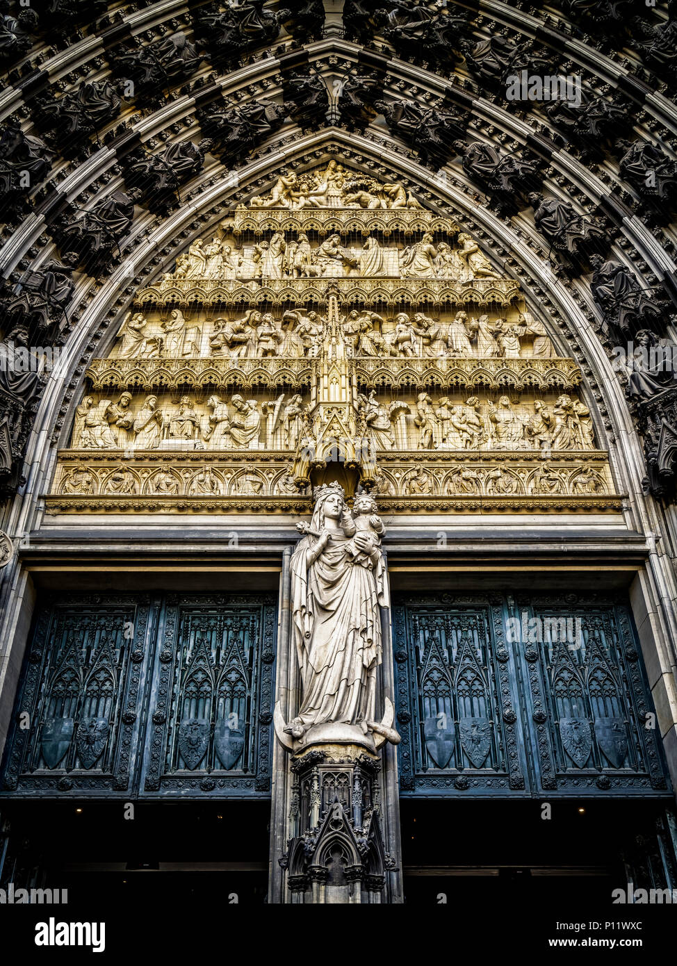 Showing the Madonna and the child is one of the most popular images of Mary in the Middle Ages. Here is Mary as Queen of Heaven. The statue was sculptured at 1880. Above the statue is a tympanum, which shows scenes of the Old and New Testament (rom the top down): the Fall of Man; Noah’s ark, Moses receiving the Tablets of the Law, and the Worship of the Golden Calf; the Annunciation, the Nativity, and the Presentation of the Christ Child in the Temple; Christ among the Doctors, the Baptism of Christ, and the Sermon on the Mount. The seated figures in the archivolts are characters from the Old  Stock Photo