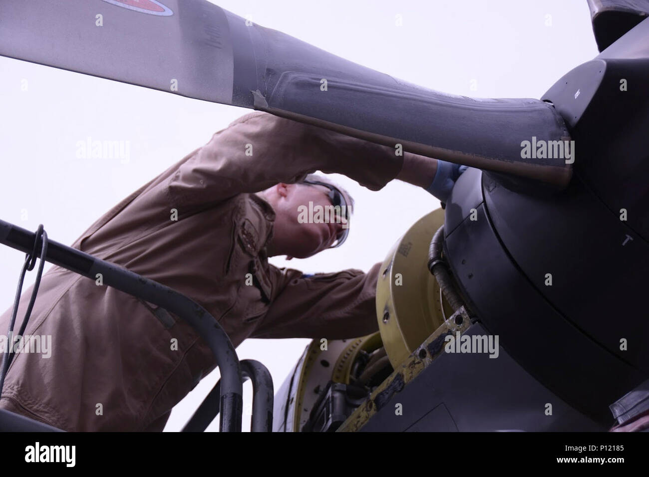 The 386th Air Expeditionary Wing Commander, U.S. Air Force Col. Charlie  Bolton, fastens the camlocks that hold the panel to the engine housing of  the C-130 Hercules aircraft as part of an