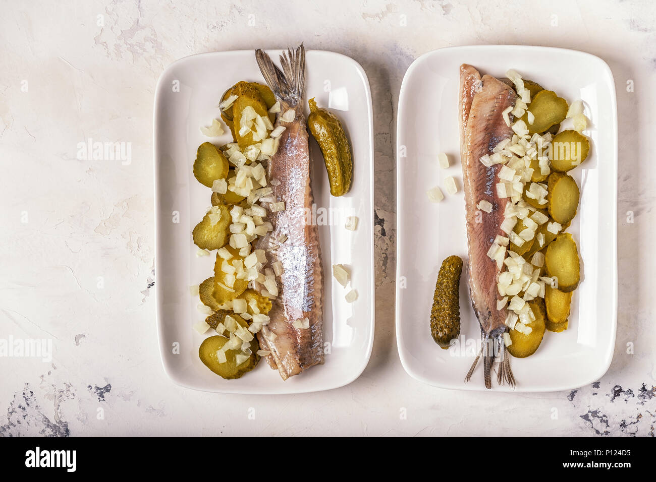 Traditional Dutch raw herring with onions and pickles on white