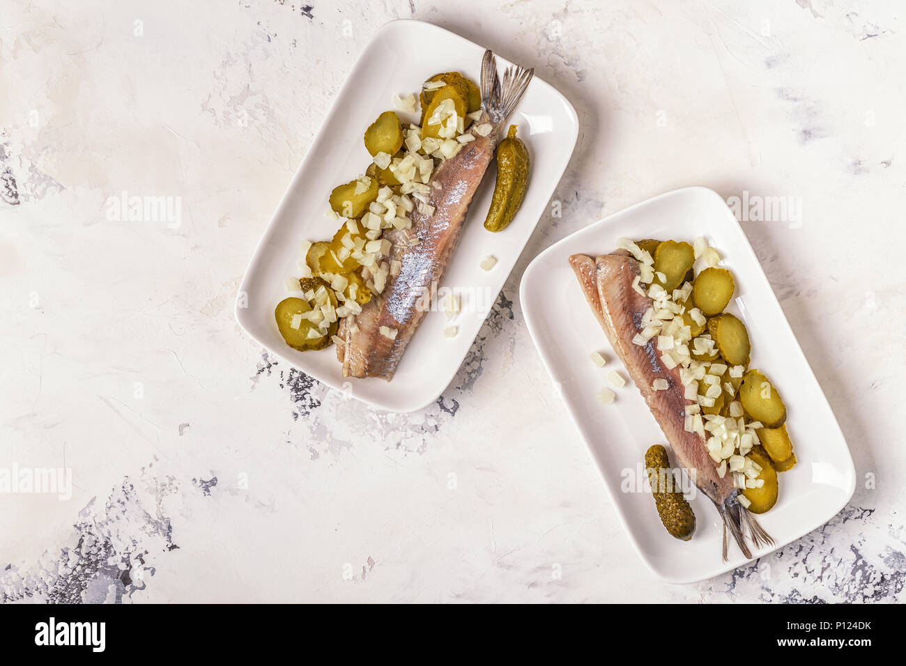 Traditional Dutch raw herring with onions and pickles on white