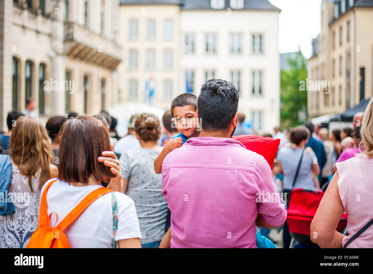 Father carries the child in his arms in the crowd, Luxembourg Stock Photo