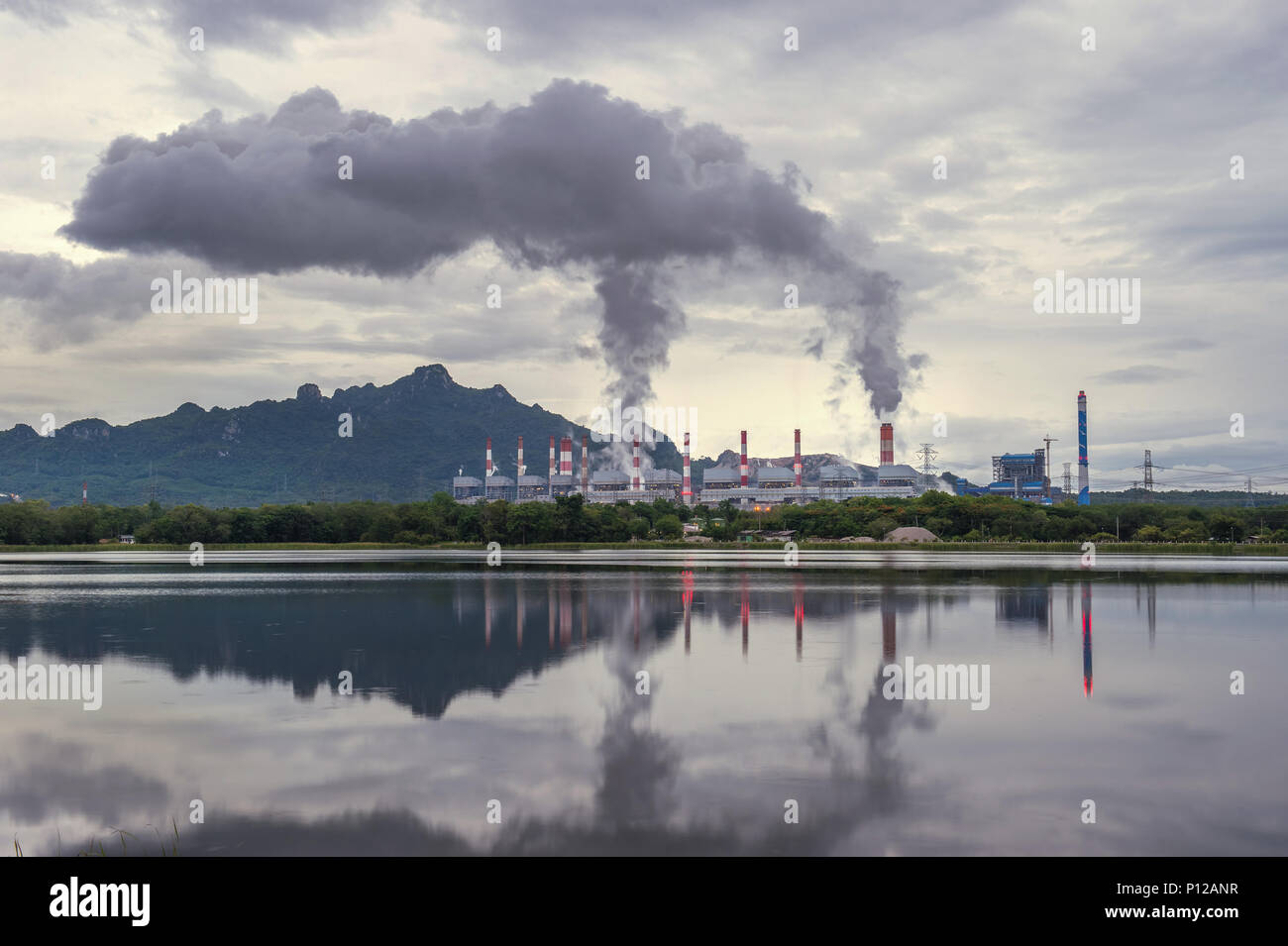 Industrial power plant with smokestack near the river. Stock Photo