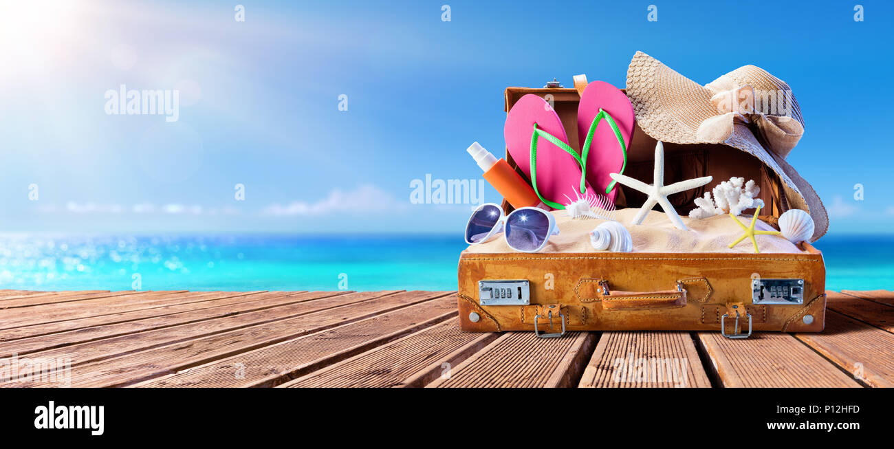 Beach Accessories In Suitcase On Wooden Pier - Travel Concept Stock Photo