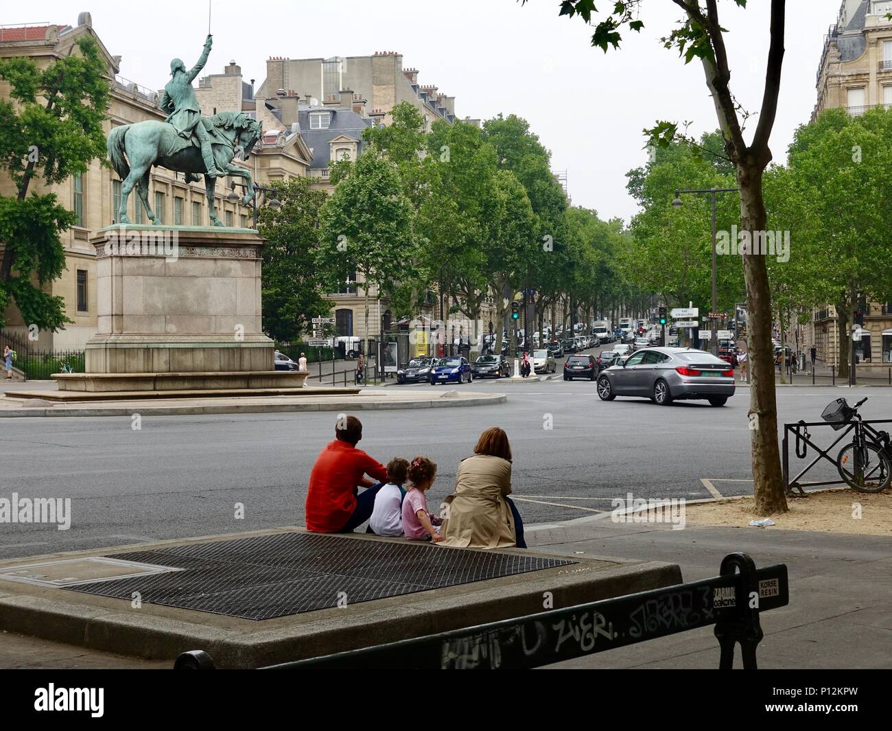 Tired family, parents, boy, girl, sitting on a curb across from a statue of George Washington, place d’Ilena, Paris, France Stock Photo