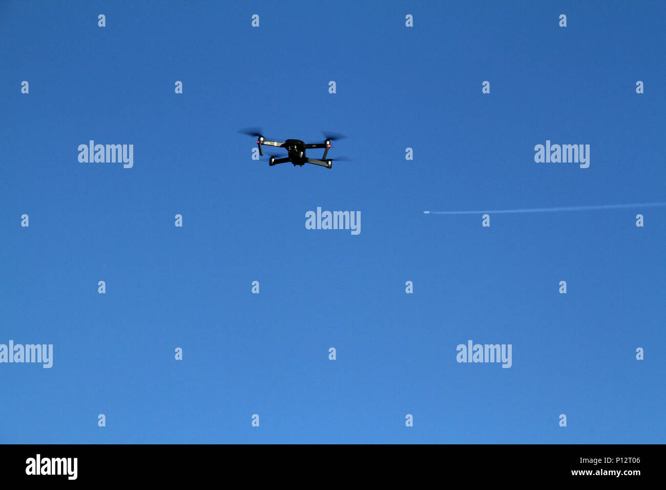 Drone flying, with airplane seen in background Stock Photo