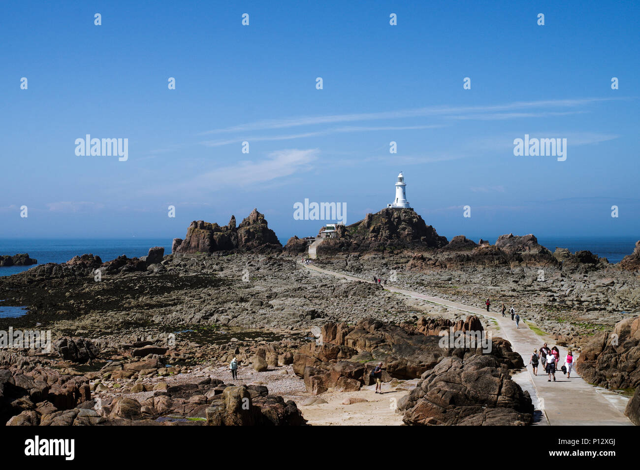 Tourists crossing the causeway to La Corbière Lighthouse in  St. Brelade - Jersey, Channel Islands Stock Photo
