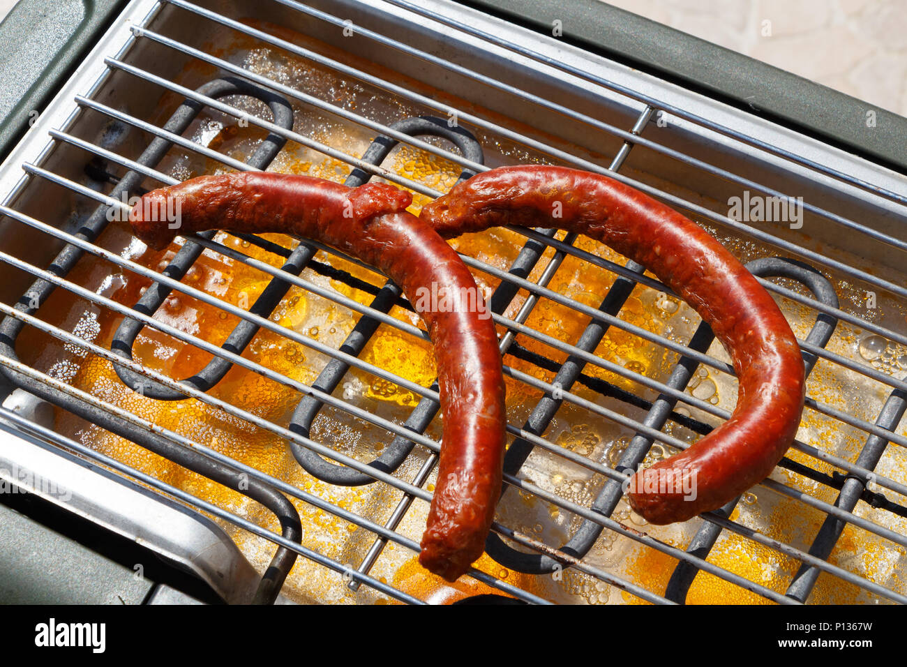 Two merguez on the grid of an electric barbecue during summer Stock Photo