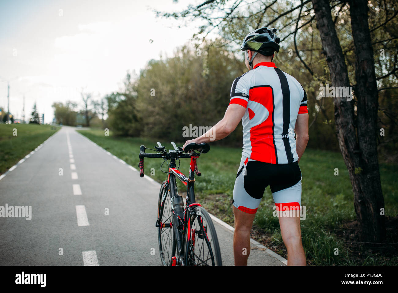 Cyclist in helmet and sportswear rides on bicycle, back view. Workout ...