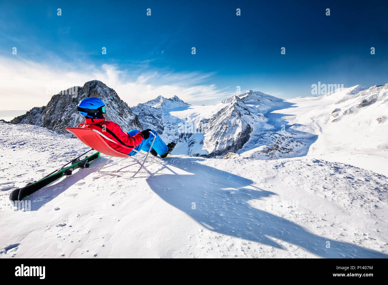 Young happy skier sitting on the top of mountains enjoying the view from Presena Glacier, Tonale, Italy Stock Photo