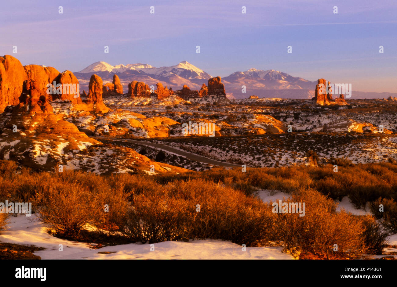 Arches National Park: near Moab, view of distant horizon through rock formations over snow covered desert in late light, Utah, USA Stock Photo