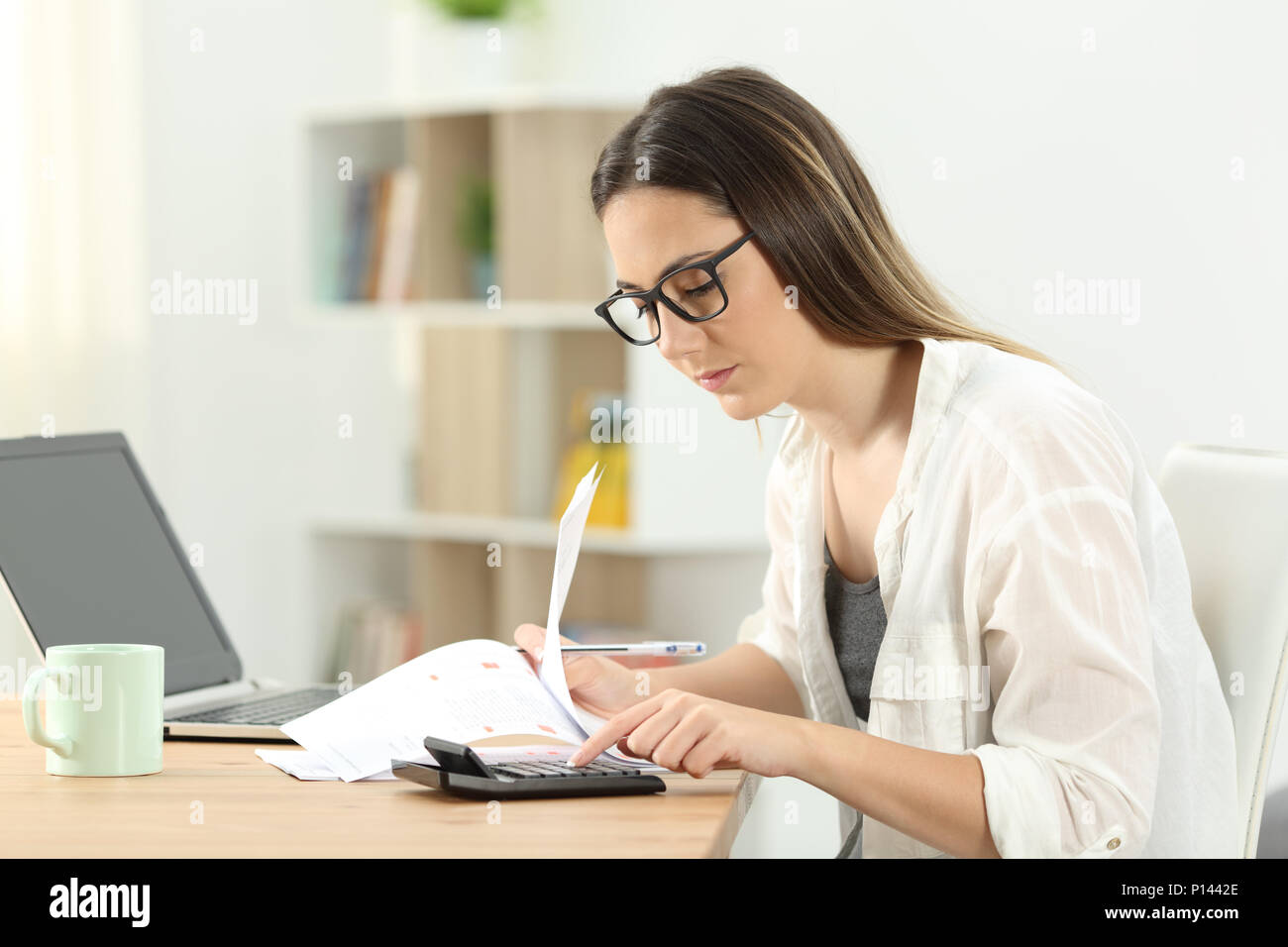 Concentrated housewife doing accounting using a calculator at home Stock Photo