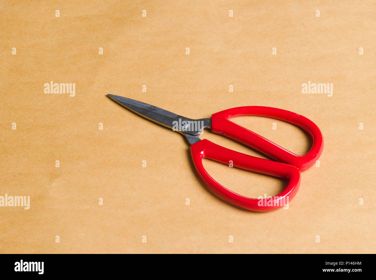 red scissors on brown background Stock Photo