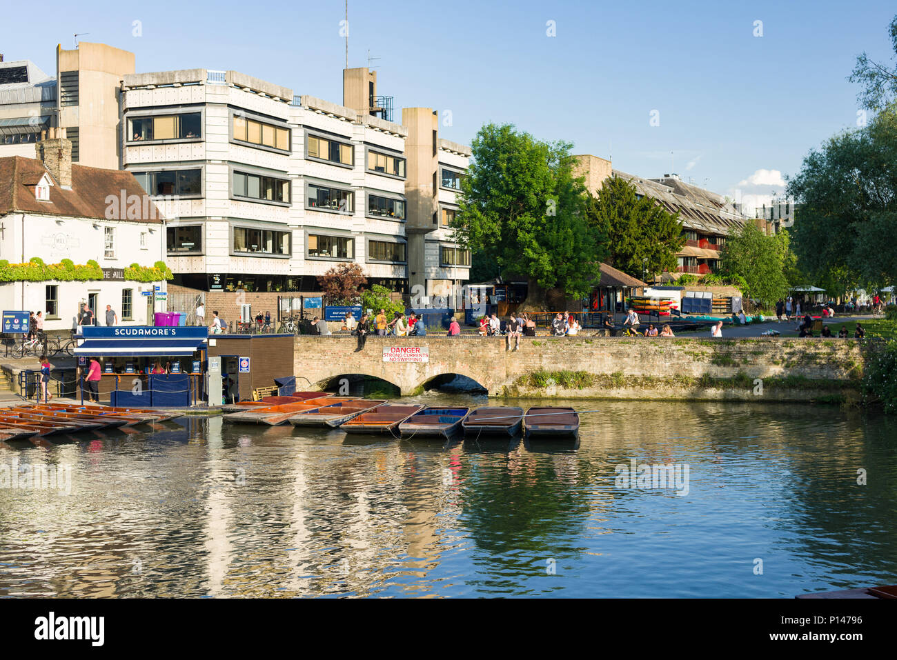 Punt boats moored on the river Cam as people walk alongside it on a sunny Summer afternoon, Cambridge, UK Stock Photo