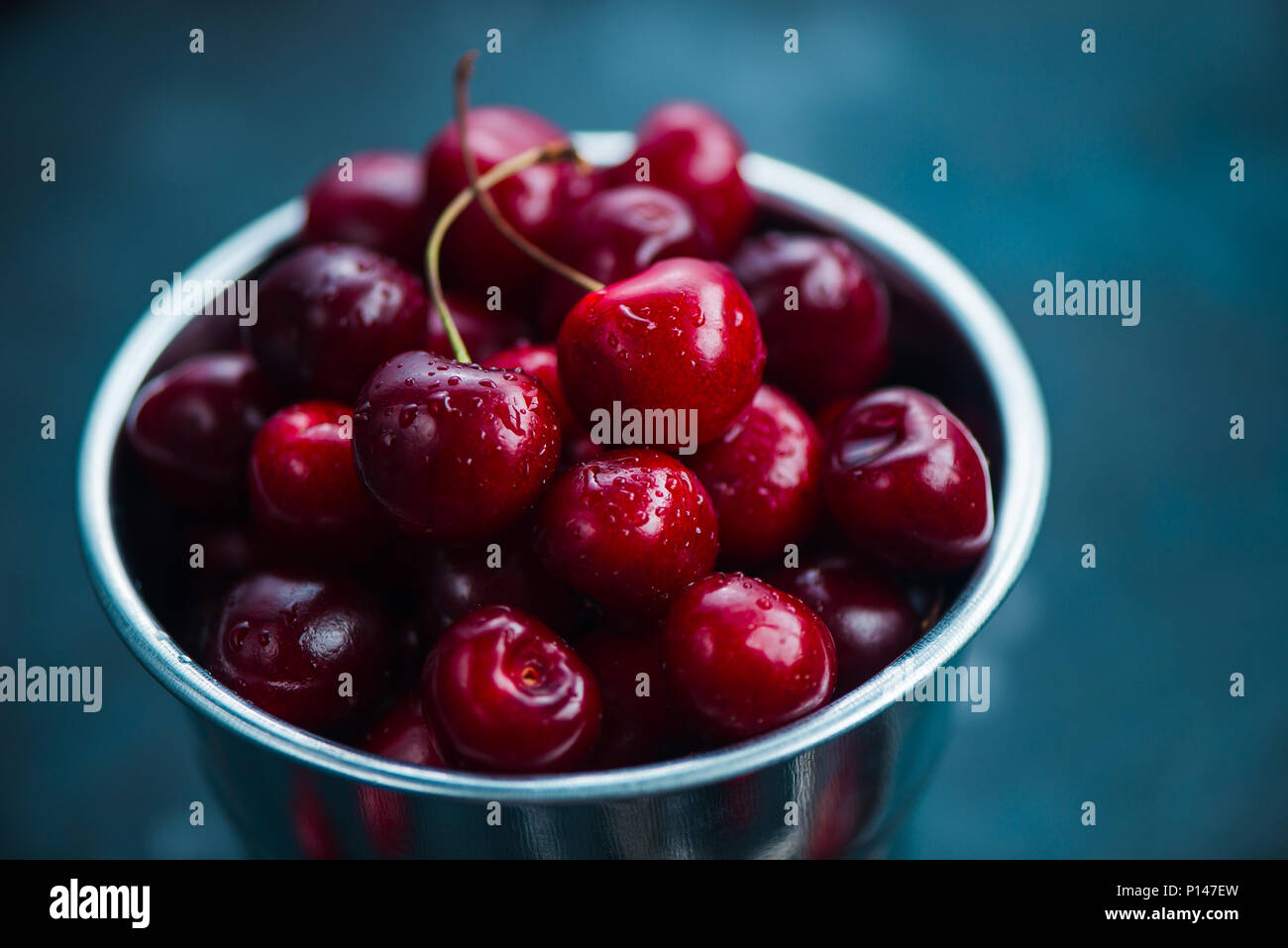 Cherries with a small metal bucket on a grey concrete background, summer berries concept with copy space. Neutral color tones still life Stock Photo